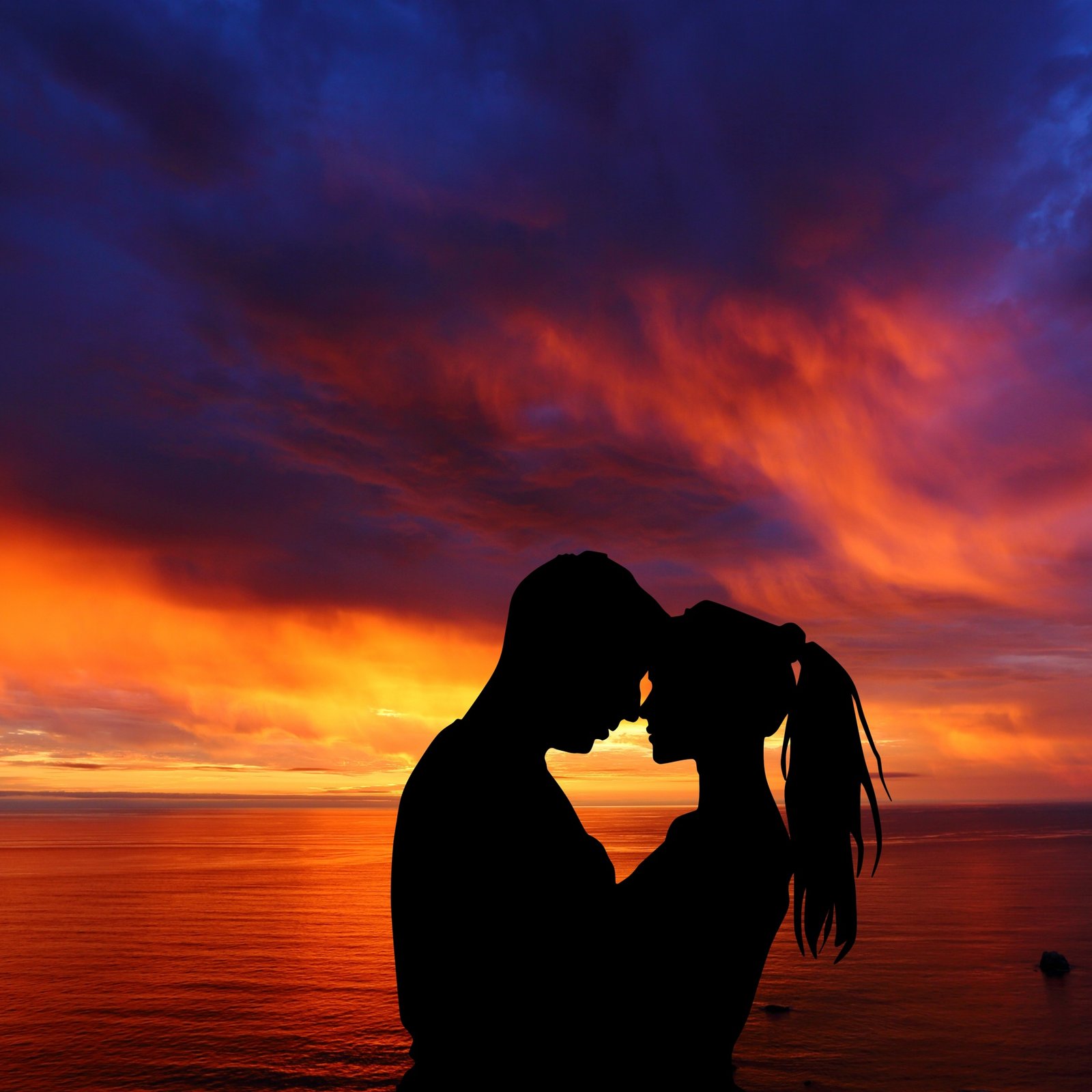 Silhouette of a couple by the sea at sunset