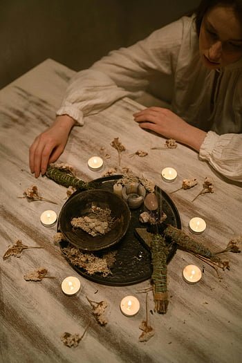 Woman performing a candlelit white sage ritual in a serene setting